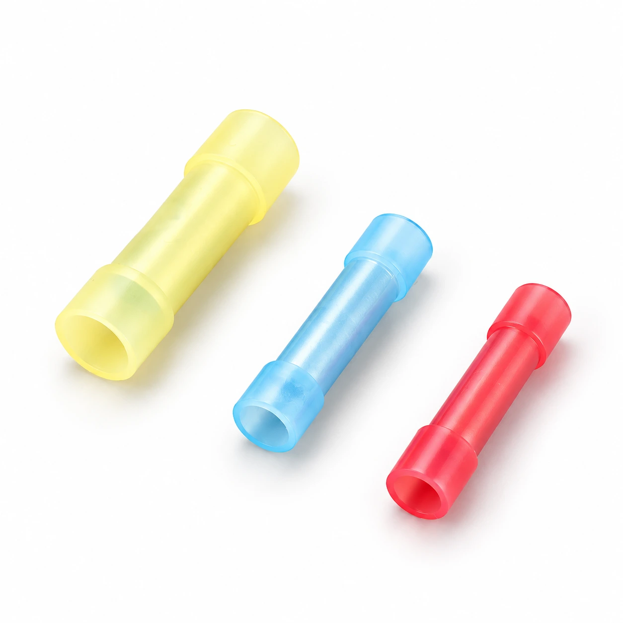 Three translucent yellow, blue and red nylon-insulated butt splice connectors with cylindrical wire-entry openings, illustrative recreation of the original TONFUL catalogue photograph
